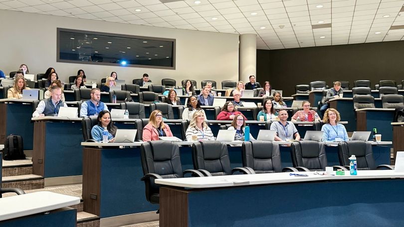 A group of Applied Systems employees listen in a lecture hall.