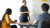 Members of the Cat Digital team work at a conference room whiteboard